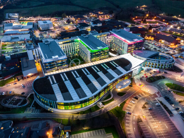 Drone Modern NHS Kings Mill hospital building lit up bright colourful at night.