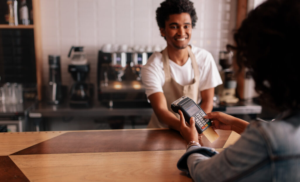 Young woman paying by credit card at cafe.