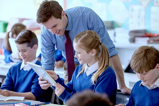 Teacher with his pupils in classroom using tablet pc