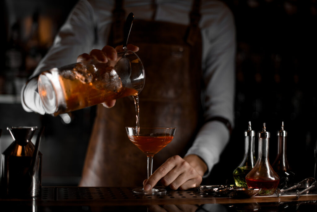 Bartender pouring an alcohol cocktail from strainer