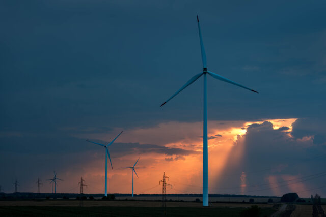 Wind turbines in field at sunset